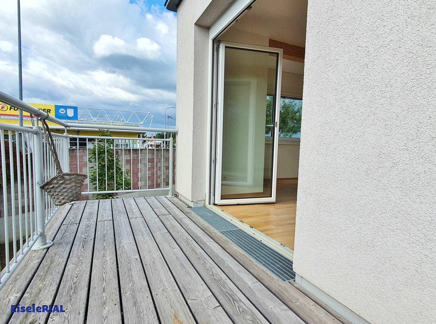 Balkon mit Holzbelag und direktem Zugang zum Innenbereich, ideal für Entspannung.