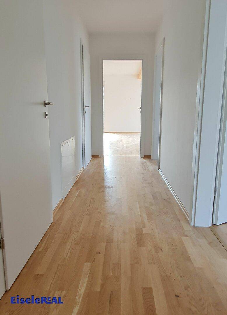 Heller Flur mit Parkettboden, der zu verschiedenen Räumen der Wohnung führt.