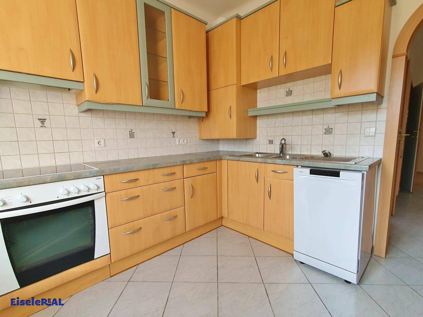 Voll ausgestattete Küche mit Holzfronten, Spülmaschine und ausreichend Arbeitsfläche.