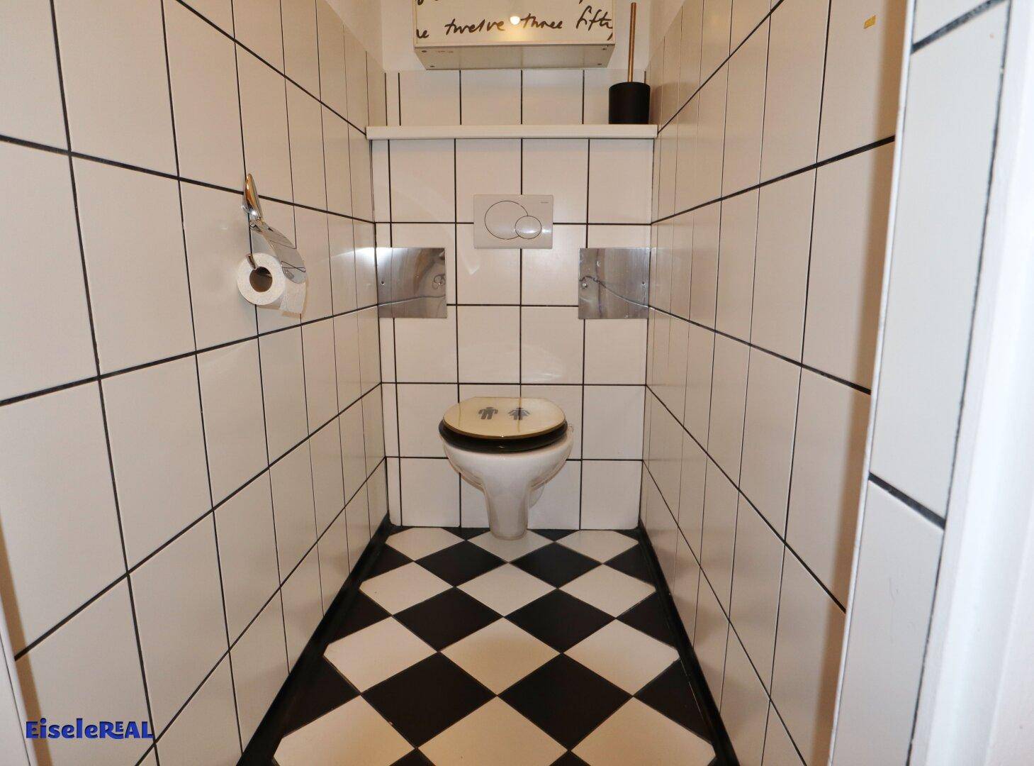 Kleines Gäste-WC mit schwarz-weiß kariertem Fliesenboden und weißen Wandfliesen.