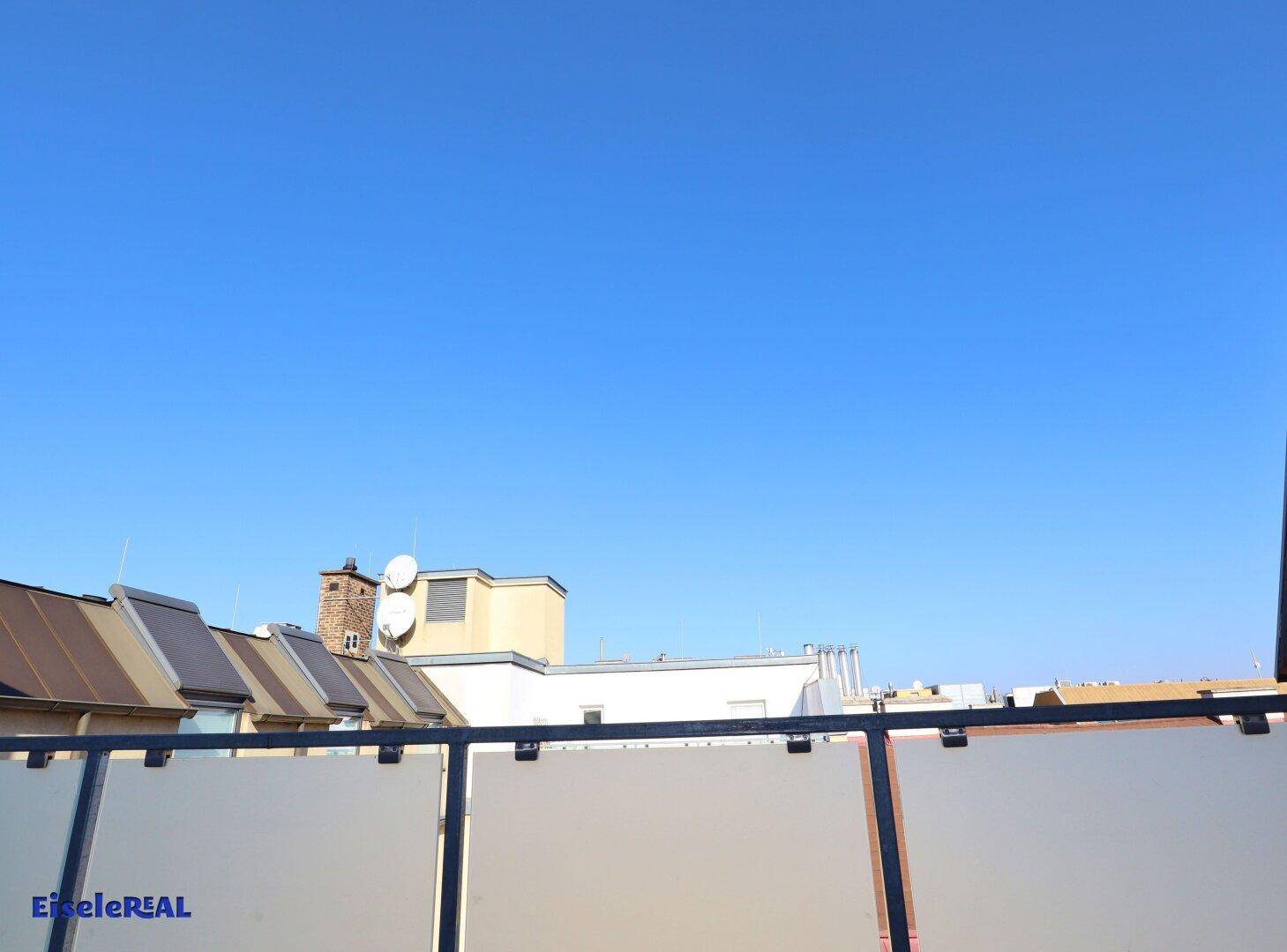 Blick über die Dächer der Stadt unter einem weiten, klaren blauen Himmel.