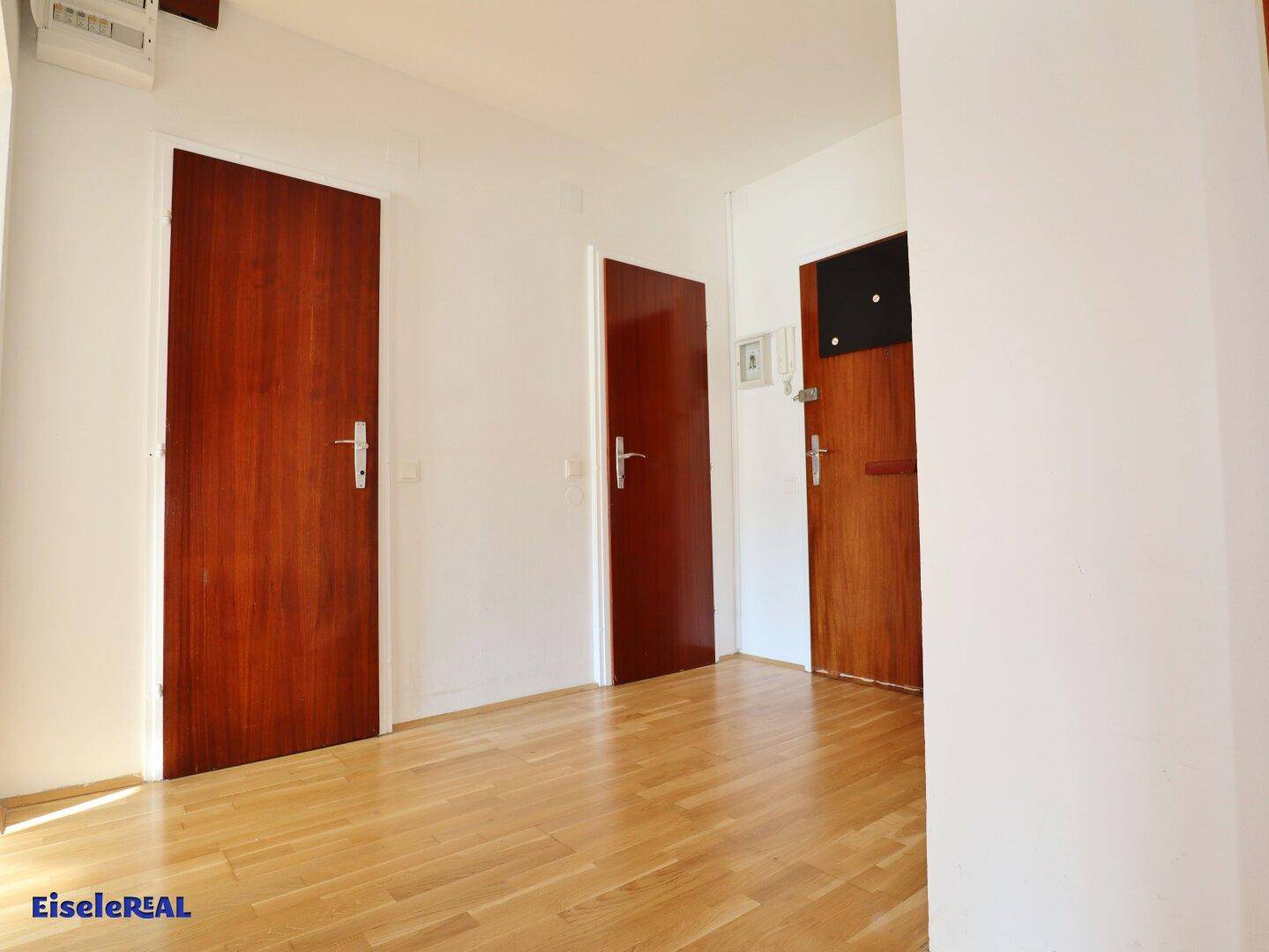 Heller Flur mit Holzboden und mehreren Holztüren, die zu verschiedenen Räumen führen.