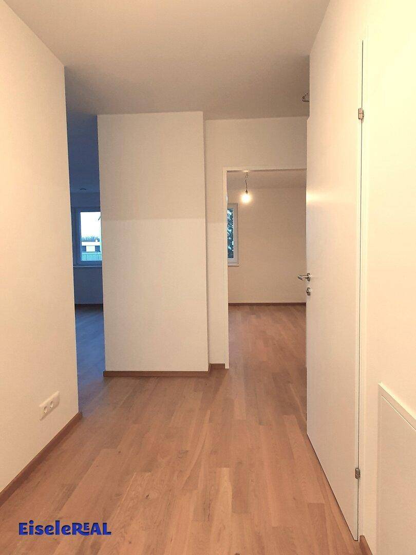 Heller Flur mit Parkettboden, der zu weiteren Räumen der Wohnung führt.