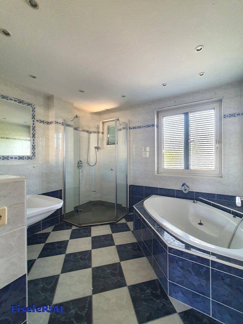 Badezimmer mit blauen und weißen Fliesen, Dusche und Eckbadewanne.