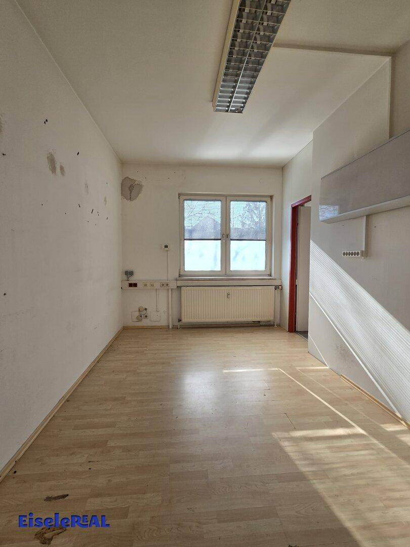 Heller, leerer Raum mit Laminatboden, Fenster und Heizkörper, ideal für ein Büro oder Schlafzimmer.