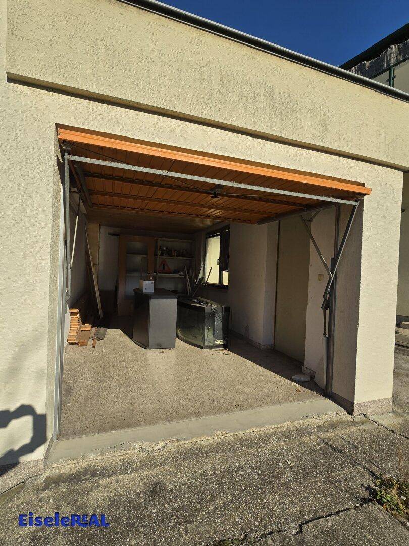 Offene Garage mit Betonboden und Blick auf den Innenraum mit Lagerflächen.