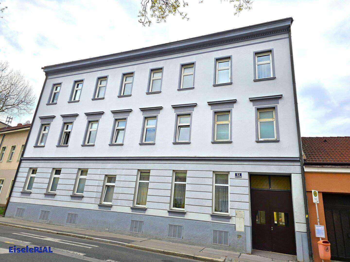Ansicht der Vorderseite des Gebäudes mit mehreren Stockwerken und traditionellen Fensterrahmen.