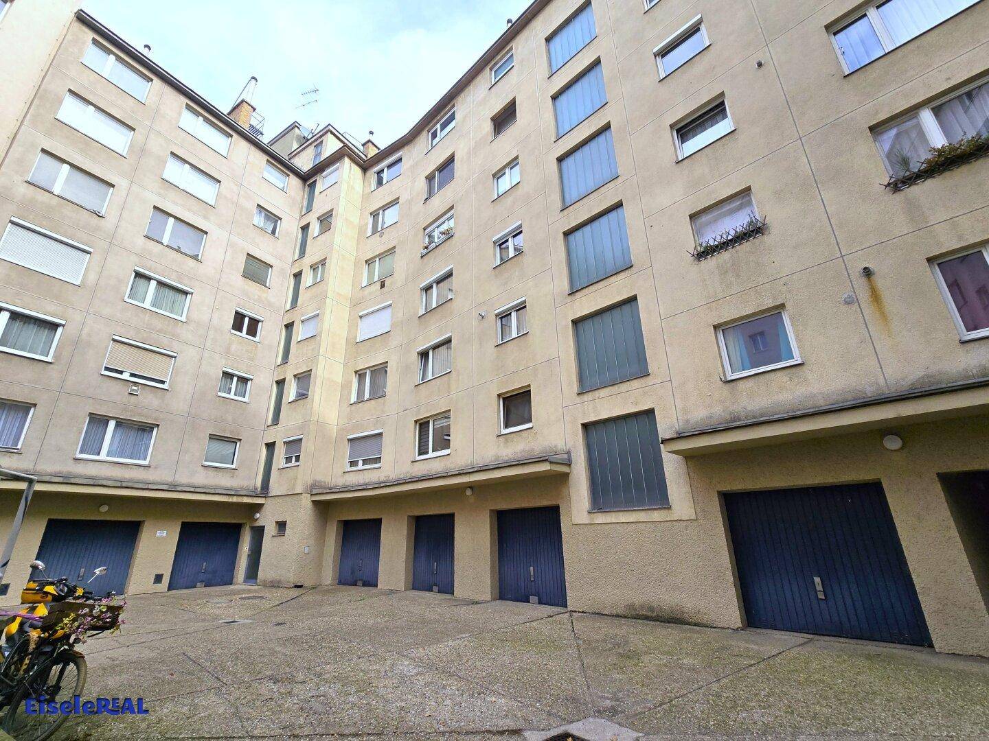 Gebäudefassade mit mehreren Fenstern und Garagentoren im Innenhof.