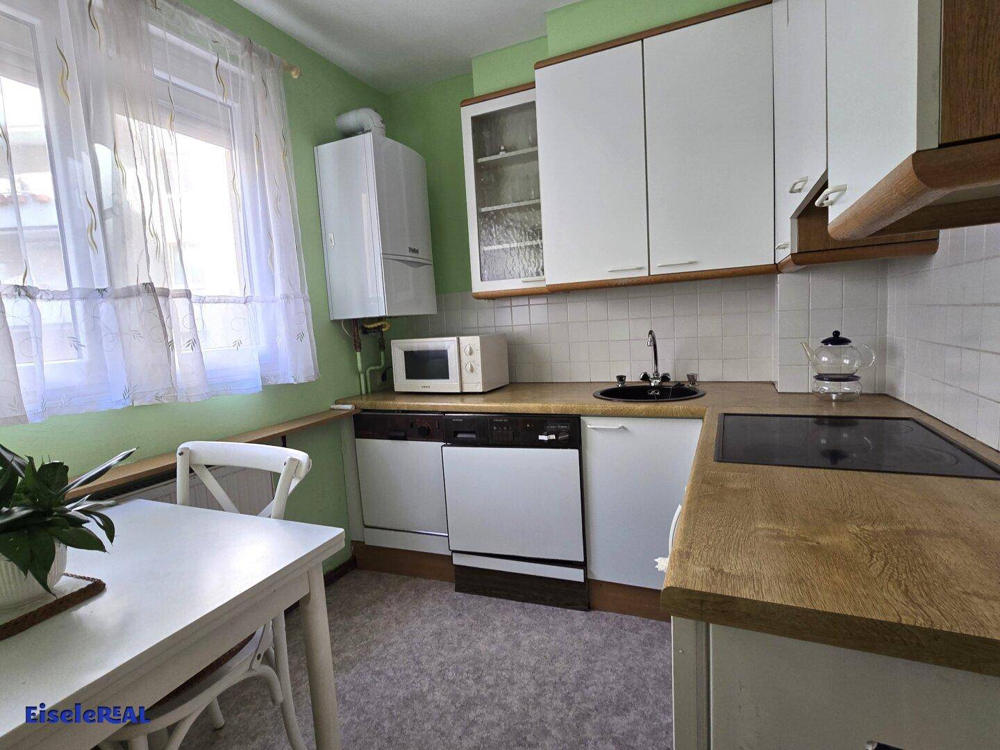 Funktionale Küche mit Holz-Arbeitsplatten, Spüle, Herd und Geschirrspüler.