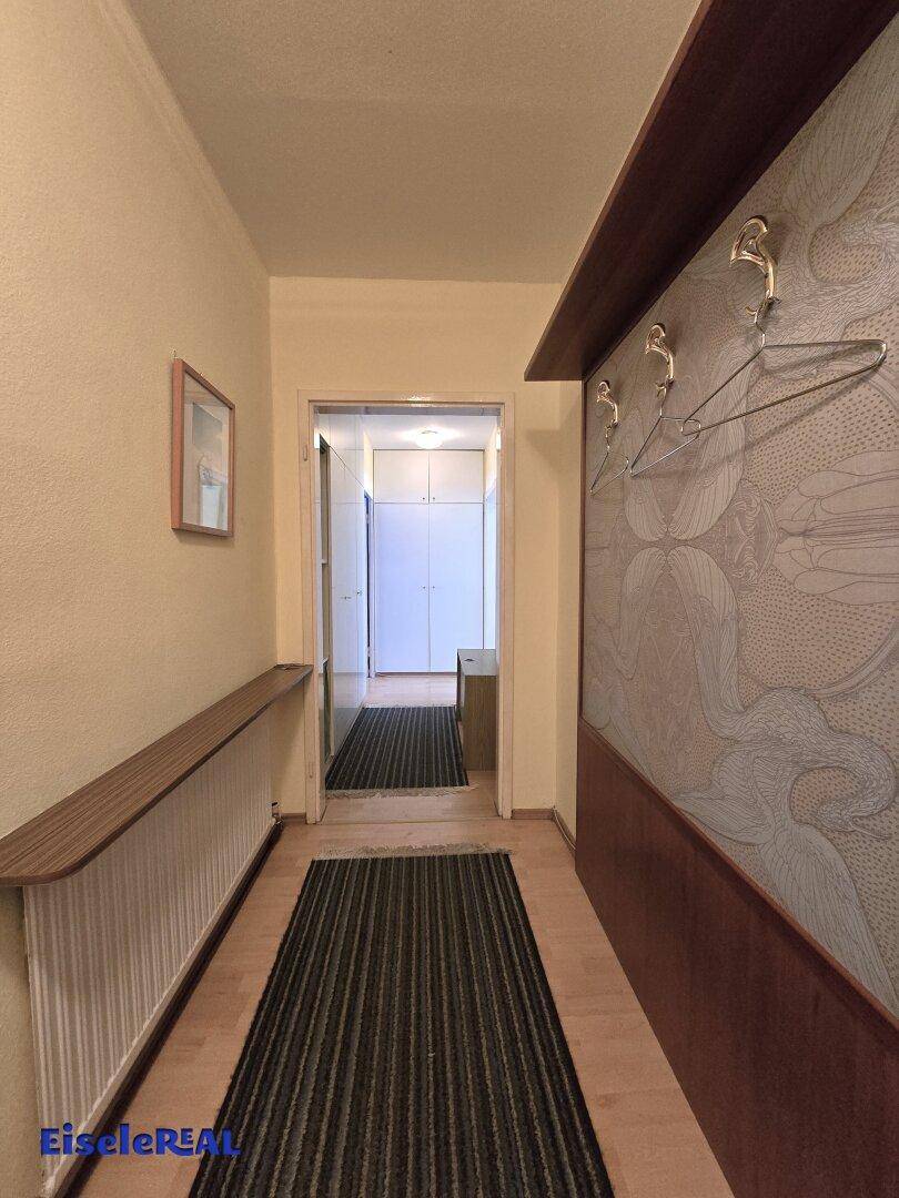 Langer Flur mit Garderobe, Holzboden und Zugang zu weiteren Räumen.