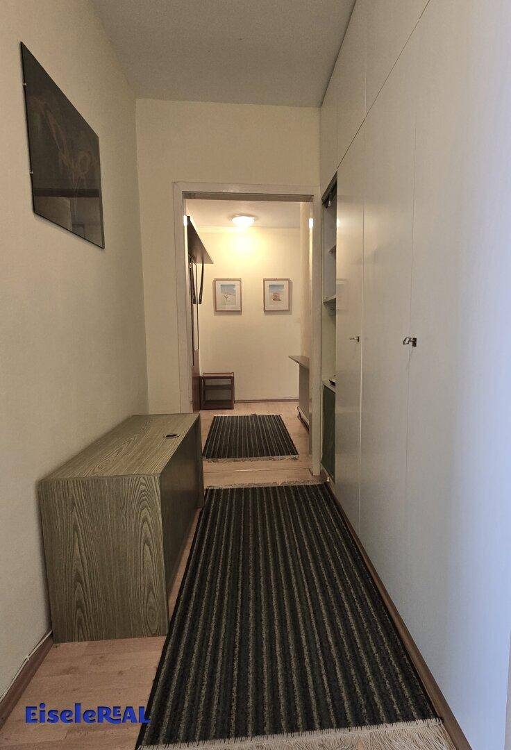 Flur mit Holzboden, weiß gestrichenen Wänden und Stauraum.
