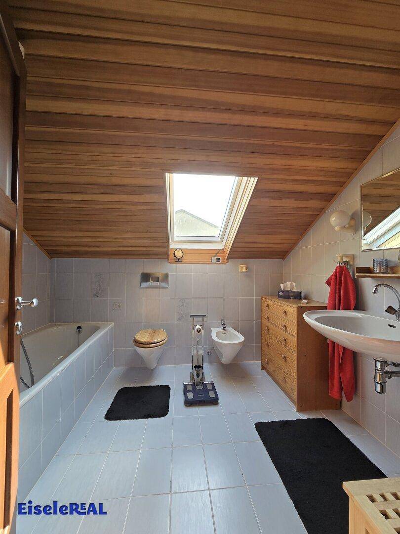 Helles Badezimmer mit Badewanne, Bidet, Dachfenster und Holzdecke.