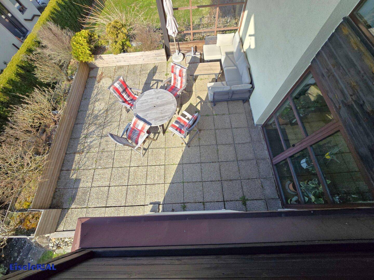 Vogelperspektive auf die große Terrasse mit Sitzgelegenheiten und angrenzendem Garten.