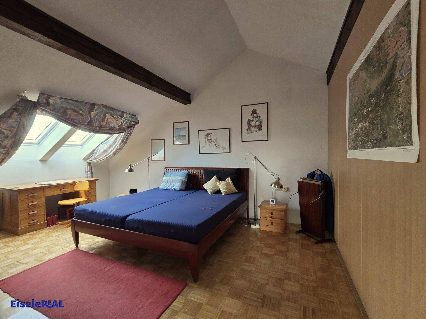 Gemütliches Schlafzimmer im Dachgeschoss mit Parkettboden und Dachfenstern.