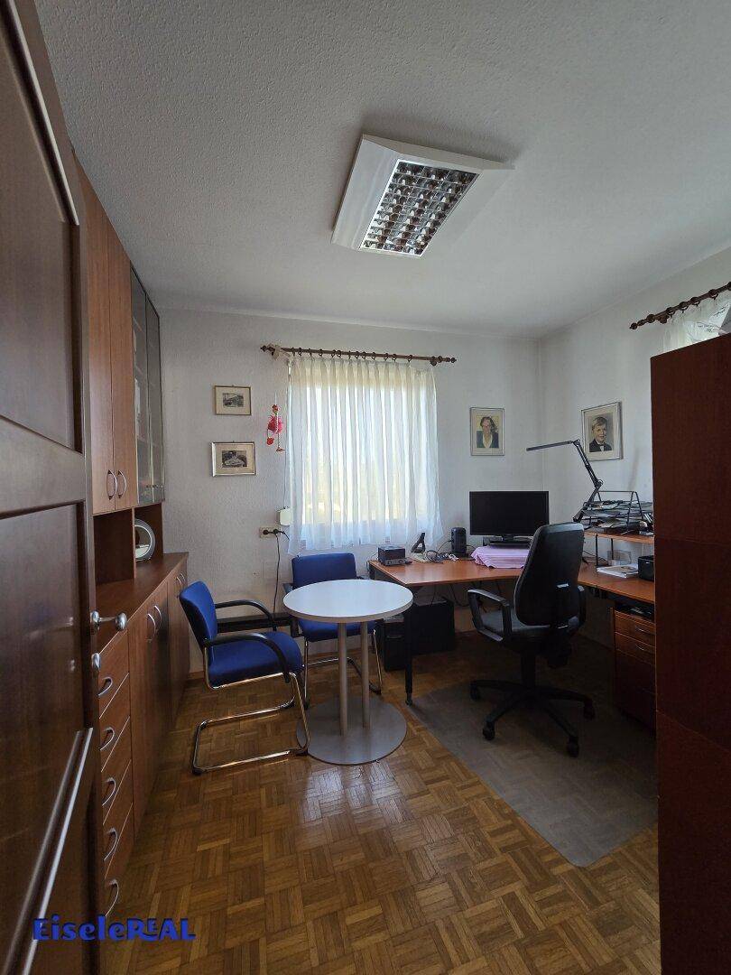 Helles Arbeitszimmer mit Schreibtisch, Bürostühlen und Einbauschränken.