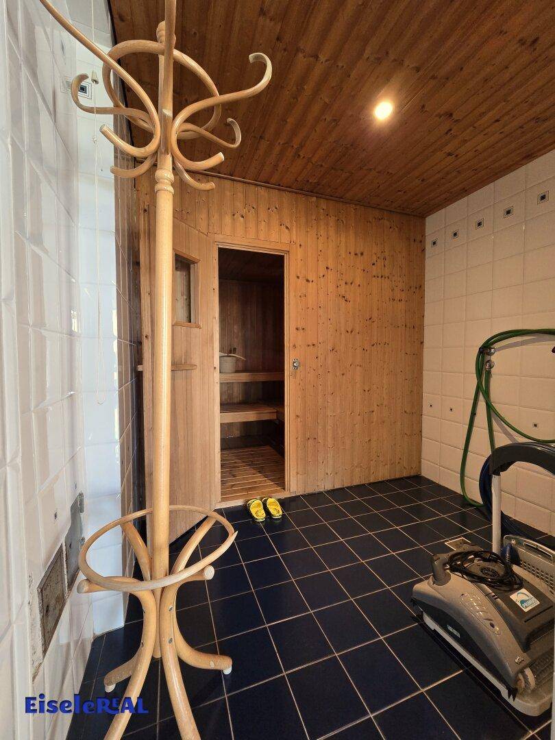 Eingang zur Sauna im Wellnessbereich mit Holzdecke und Fliesenboden.