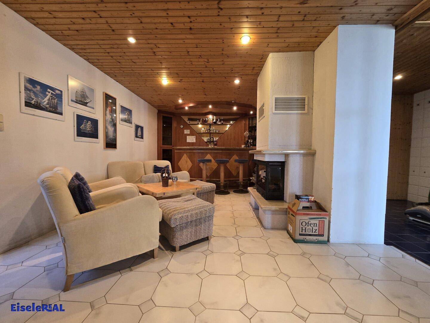 Gemütlicher Keller-Wohnbereich mit Bar, Kamin und Fliesenboden.