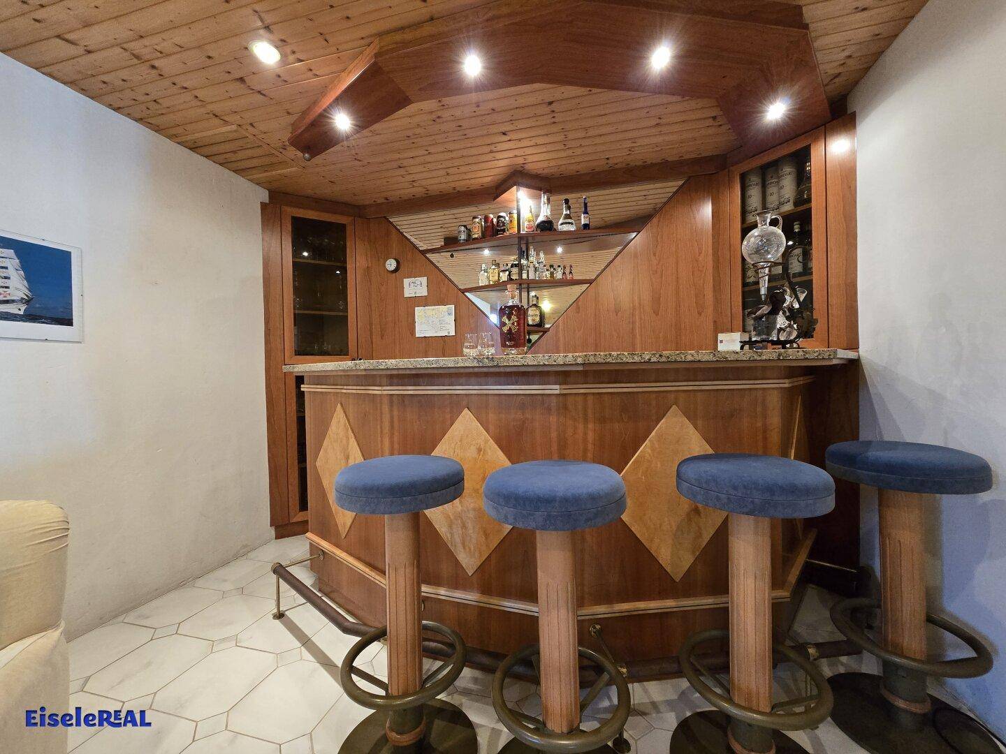 Stilvolle Hausbar im Keller mit Hockern, Holzverkleidung und Spiegeln.
