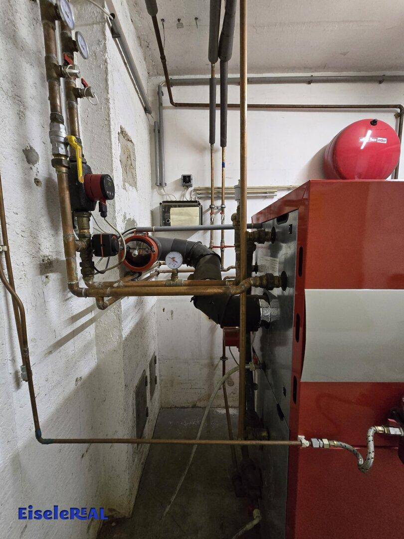 Detailansicht der Heizungsanlage mit Kupferrohren und Installationen im Keller.