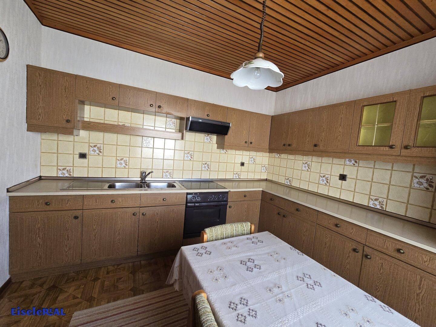 Funktionale Küche mit Holzschränken, gefliestem Fliesenspiegel und Essbereich.