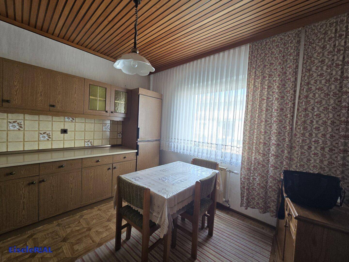 Helle Küche mit Holzdecke, Esstisch und Fenster für natürliches Licht.