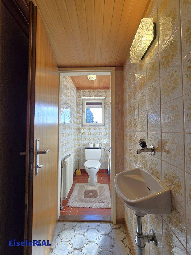 Separates Gäste-WC mit kleinem Waschbecken und Fenster.