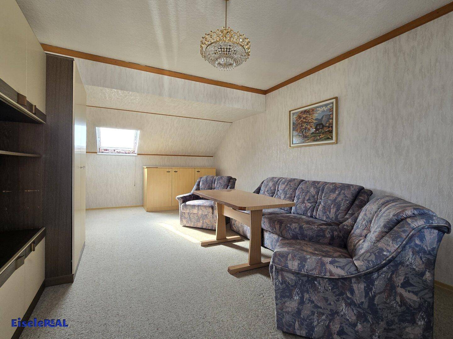 Gemütliches Wohnzimmer im Dachgeschoss mit Teppichboden und Dachfenster.