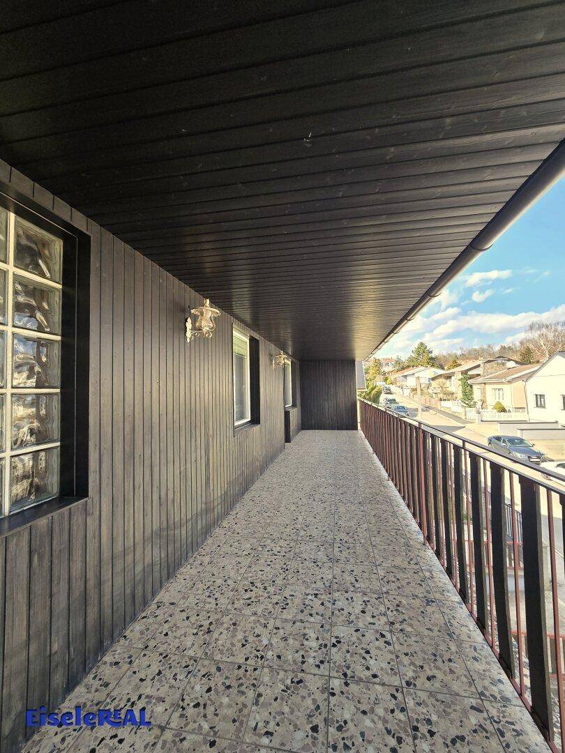 Überdachter Balkon mit Fliesenboden und Blick auf die Straße und Nachbarschaft.