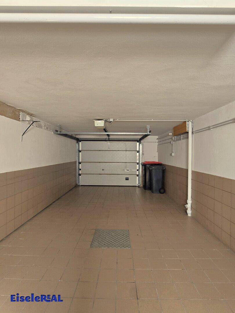 Geräumige Garage mit Fliesenboden und automatischem Garagentor.