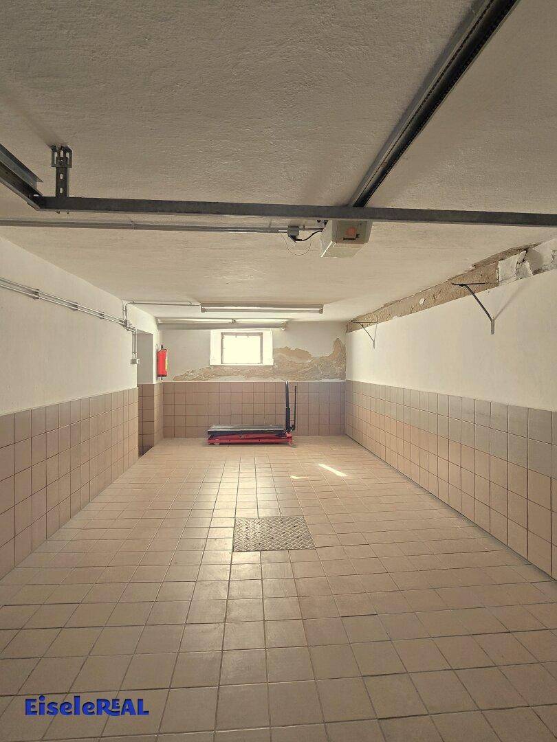 Helle Garage mit Fliesenboden, Fenster und ausreichend Platz.