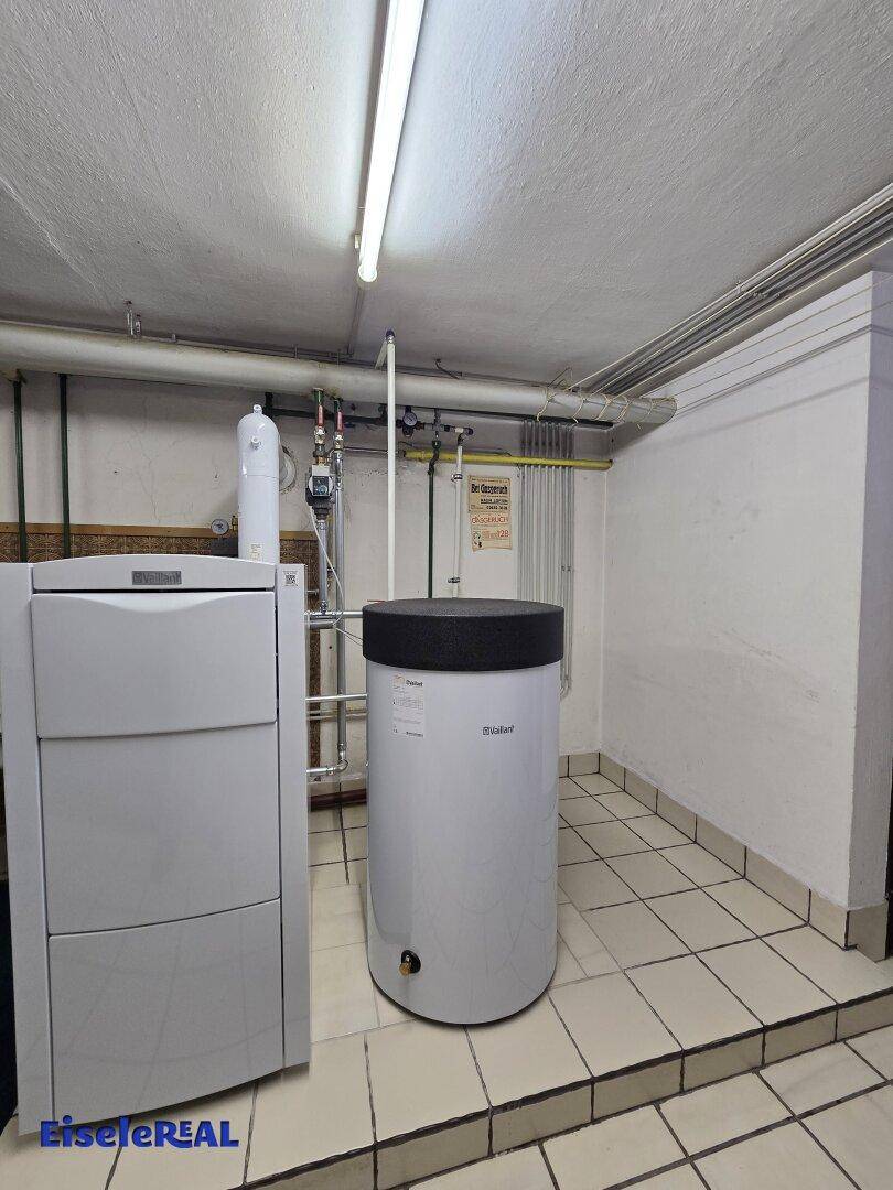 Moderne Heizungsanlage mit Warmwasserspeicher im Kellerraum.