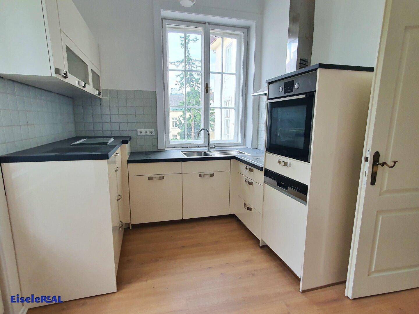 Funktionale Küche mit Einbaugeräten, hellen Schränken und Fenster.