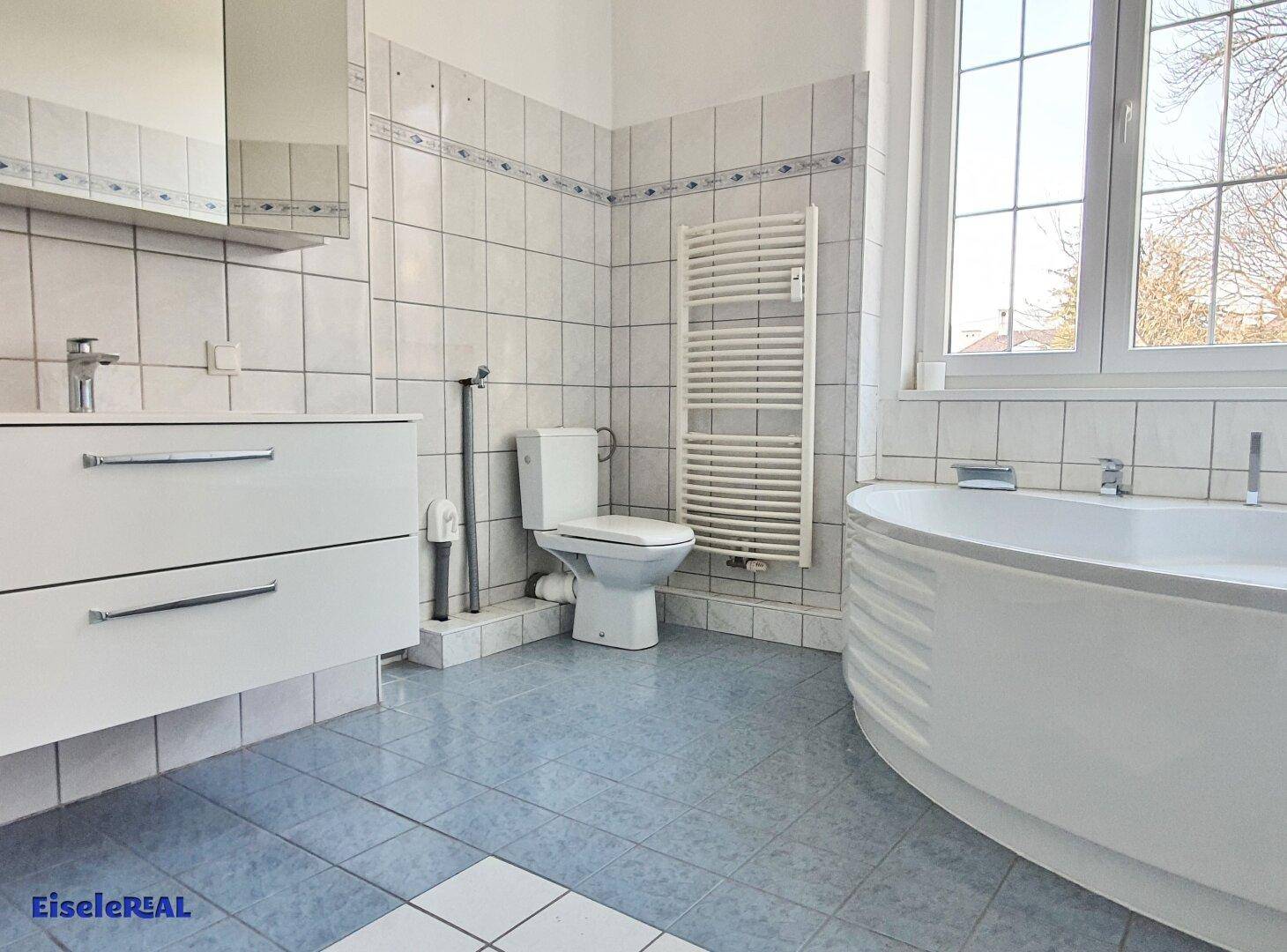 Geräumiges Badezimmer mit Eckbadewanne, Doppelwaschbecken und beheiztem Handtuchhalter.