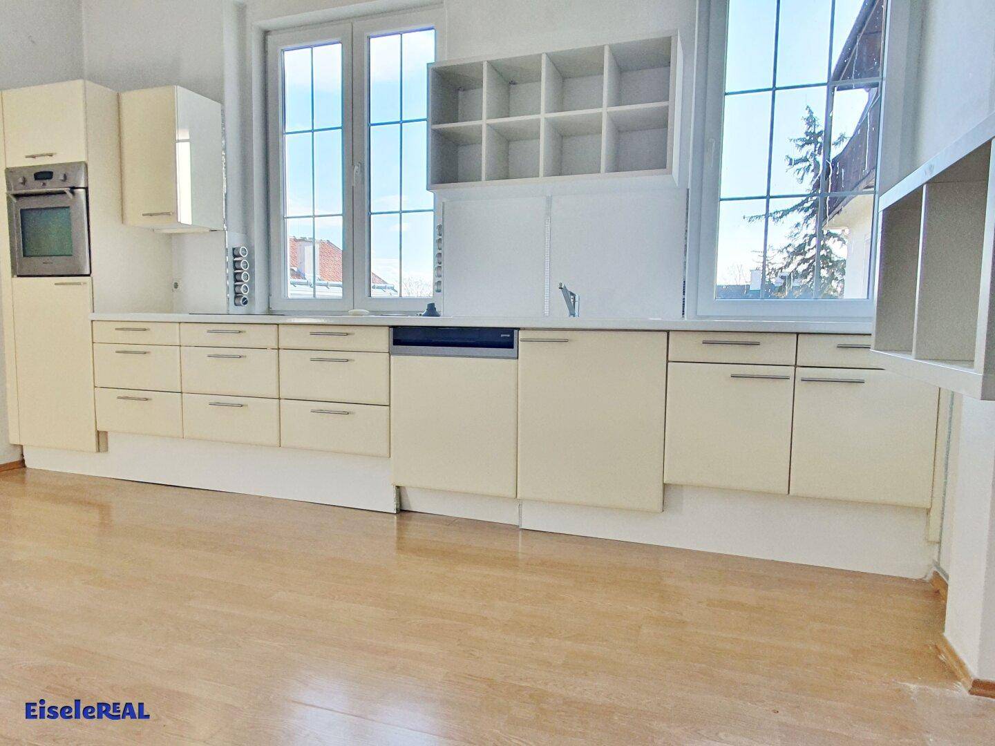 Moderne Einbauküche mit hellen Schränken, integrierten Geräten und Fenster.