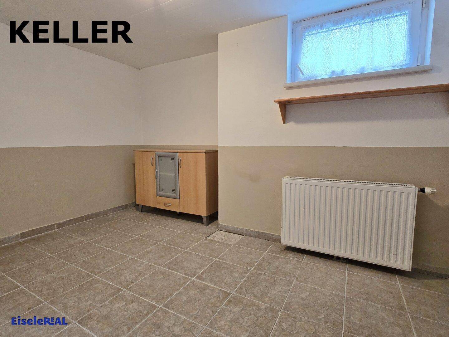 Kellerraum mit Fliesenboden, Heizkörper und einem Schrank, nutzbar als Hobby- oder Abstellraum.