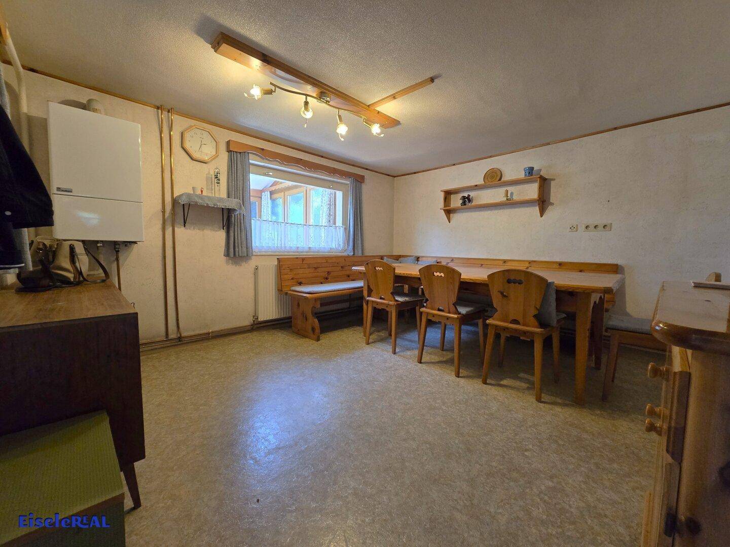 Rustikaler Essbereich mit Holzbänken, Esstisch und Blick in den Garten.