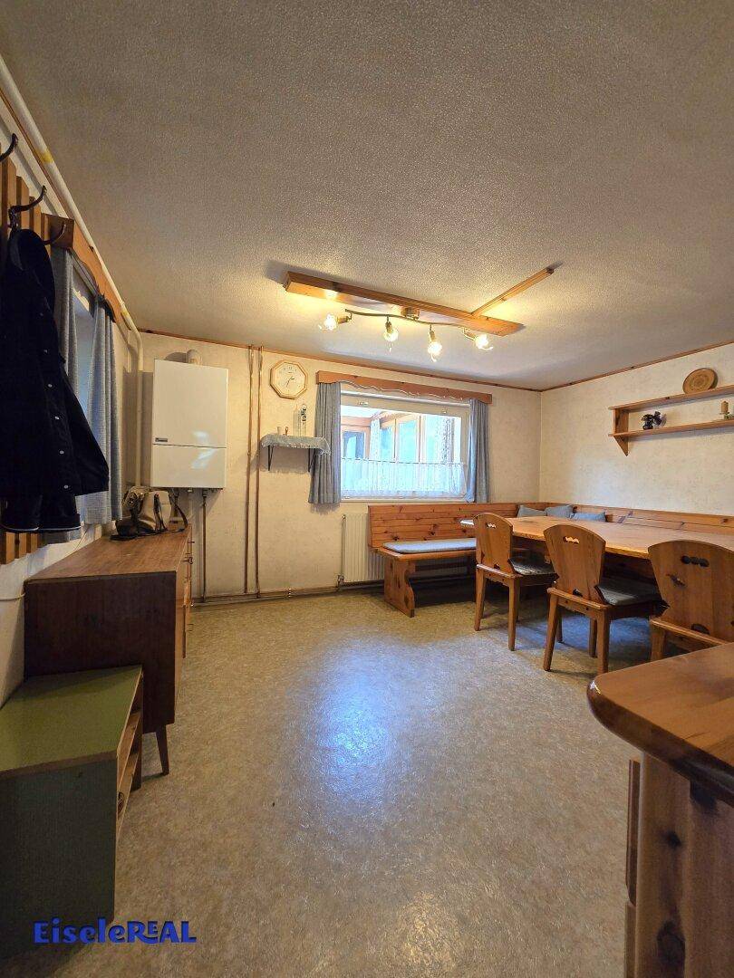 Gemütlicher Essbereich mit traditionellen Holzmöbeln und Fenster mit Blick ins Grüne.