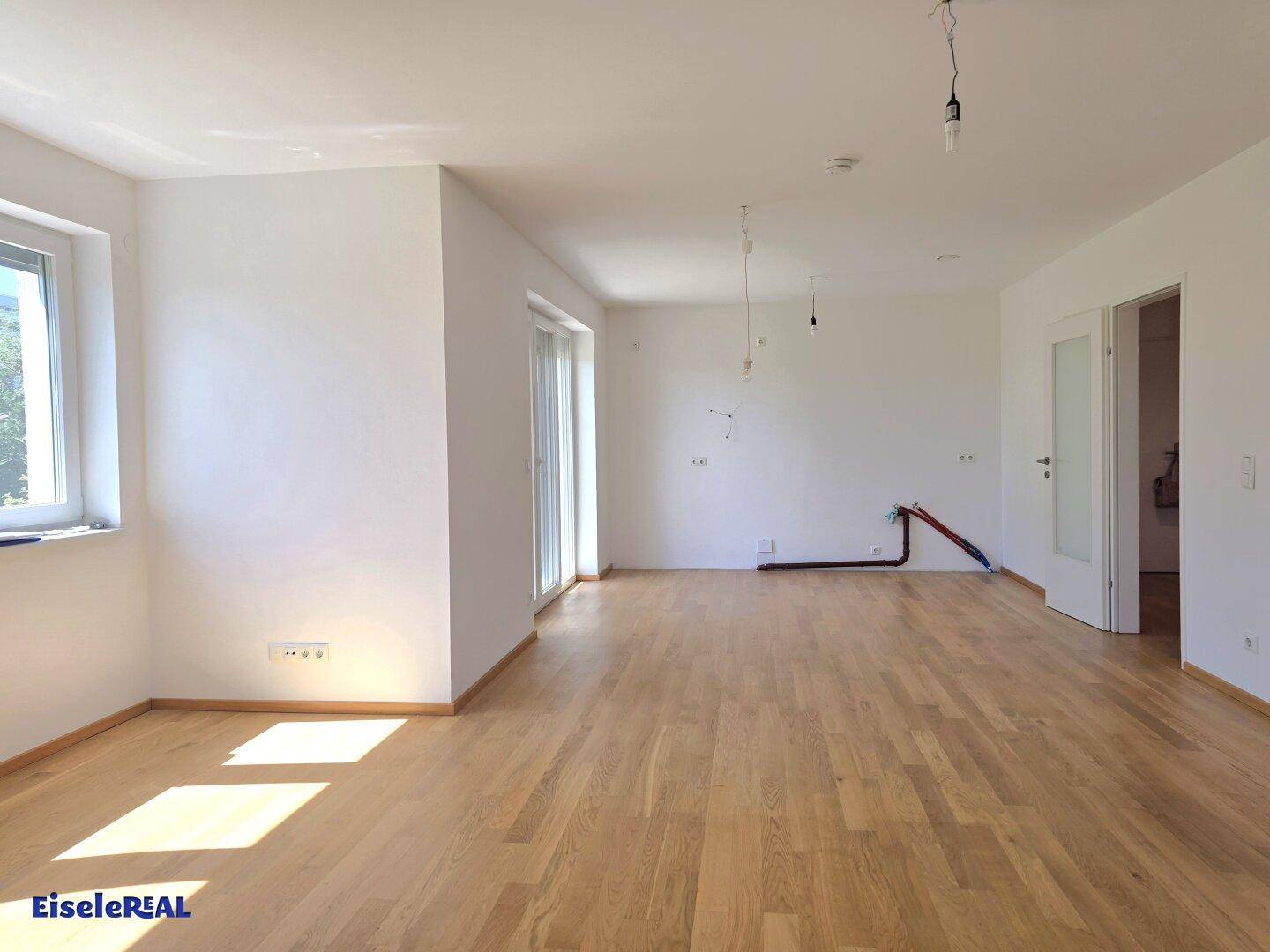 Lichtdurchfluteter Wohnbereich mit hellem Eichenparkett und weiß gestrichenen Wänden, ideal für individuelle Gestaltung.
