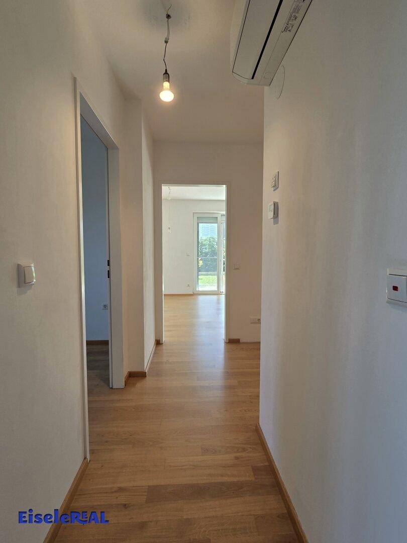 Heller Flur mit Eichenparkettboden und Zugang zu verschiedenen Räumen, ausgestattet mit Klimaanlage.