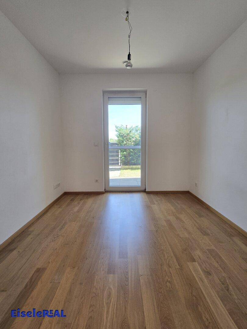 Ruhiges Schlafzimmer mit Eichenparkett und direktem Zugang zum Außenbereich, ideal für Entspannung und Licht.