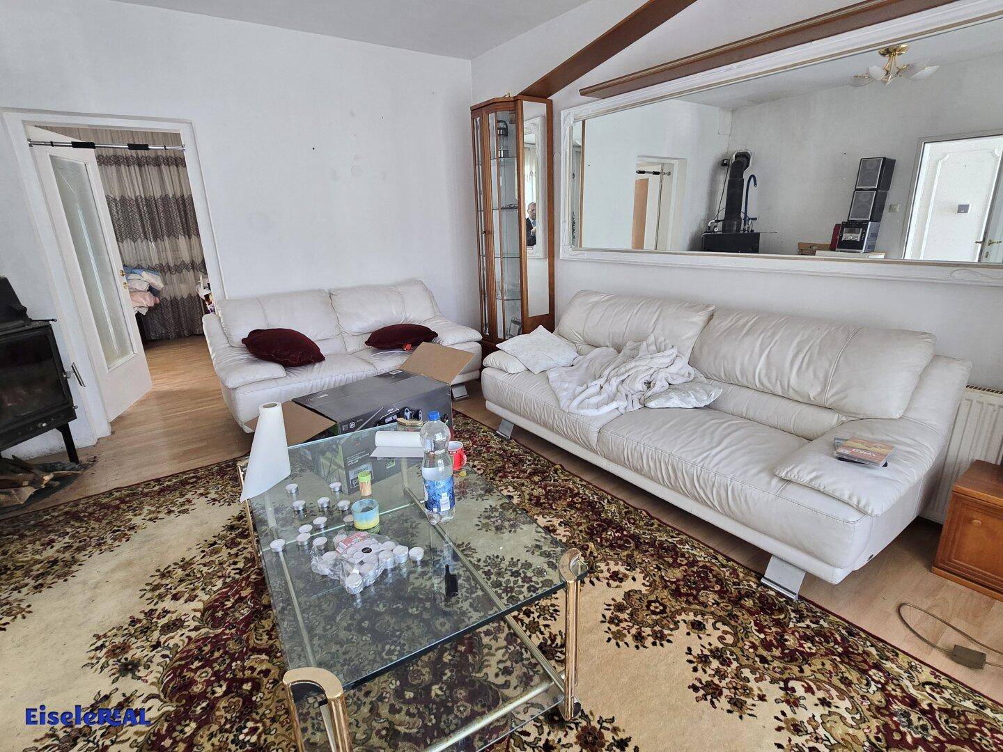 Wohnzimmer mit zwei weißen Sofas, Teppich und großem Spiegel an der Wand.