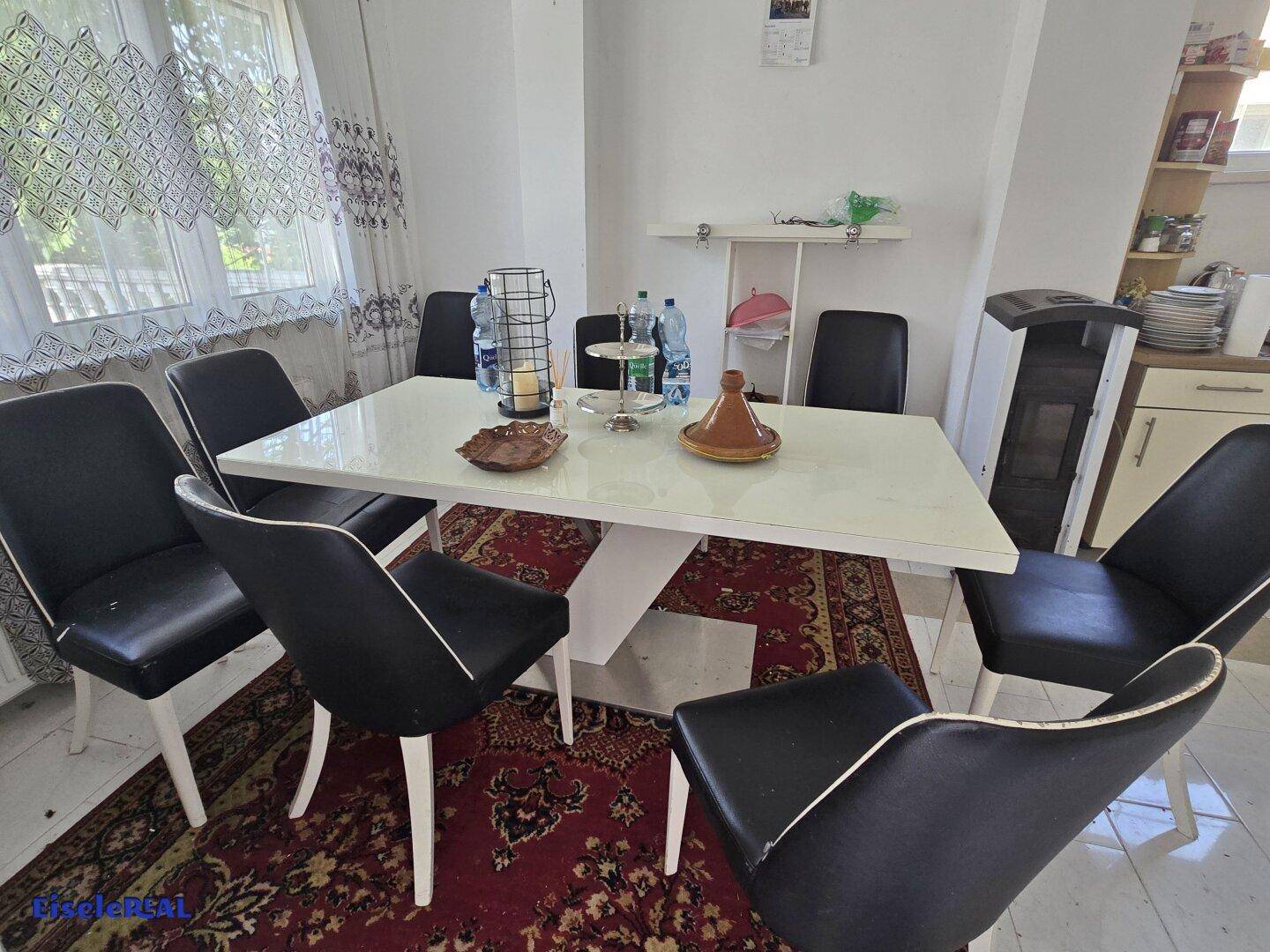 Esszimmer mit modernem Esstisch, schwarzen Stühlen und gemustertem Teppich.