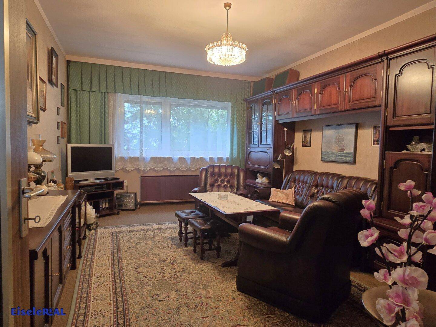 Traditionelles Wohnzimmer mit klassischer Einrichtung, Teppichboden und einem Kronleuchter.