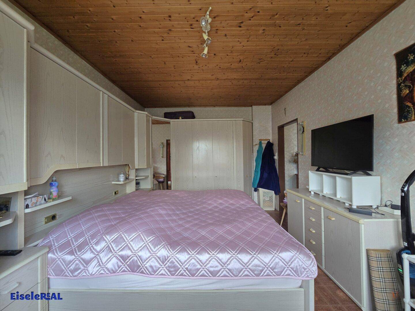 Geräumiges Schlafzimmer mit umfassenden Einbauschränken und einer Holzdecke.