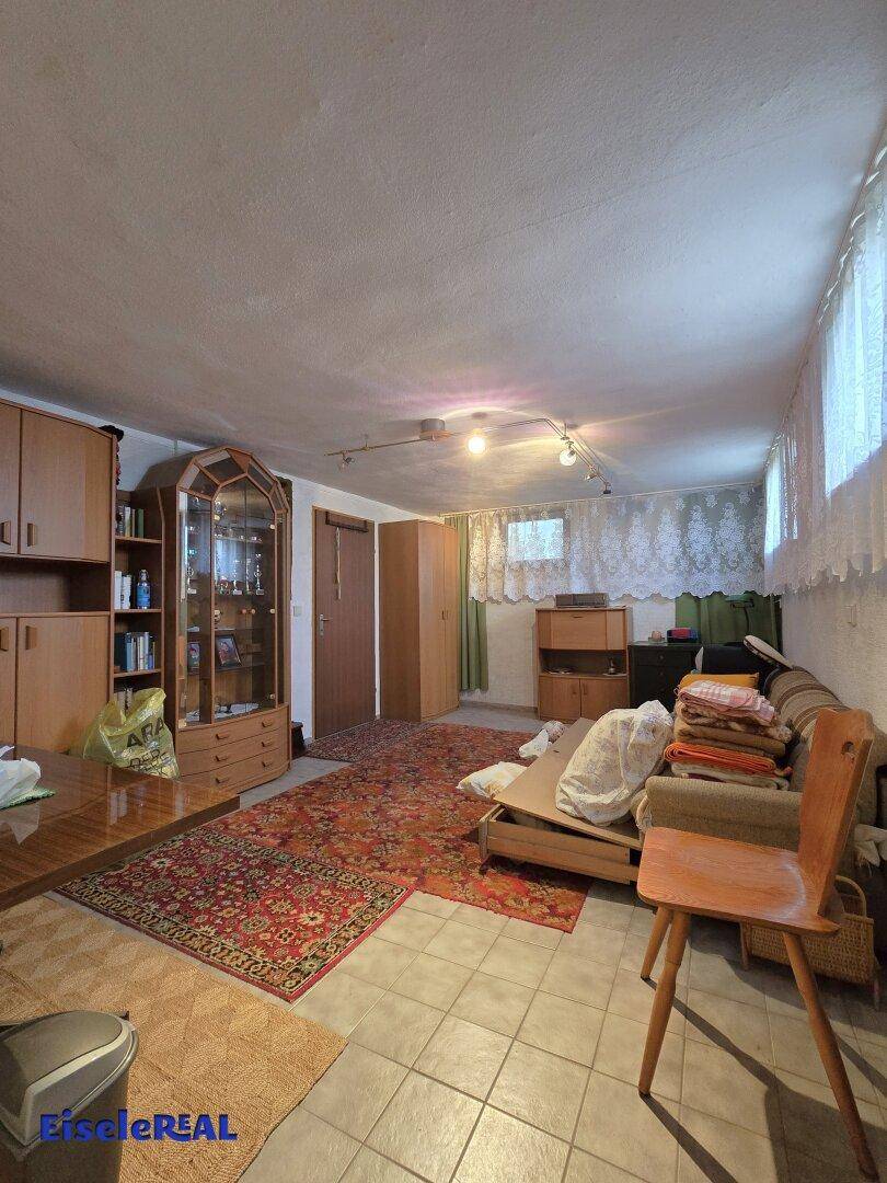 Ausgebauter Kellerraum mit Möbeln, Teppich und vielseitigen Nutzungsmöglichkeiten.