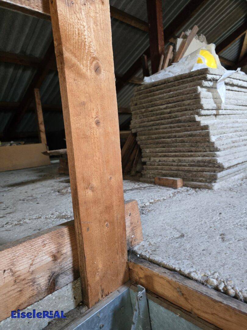 Dachbodenbereich mit gestapelten Baumaterialien und sichtbaren Holzbalken, ideal für zukünftige Projekte.