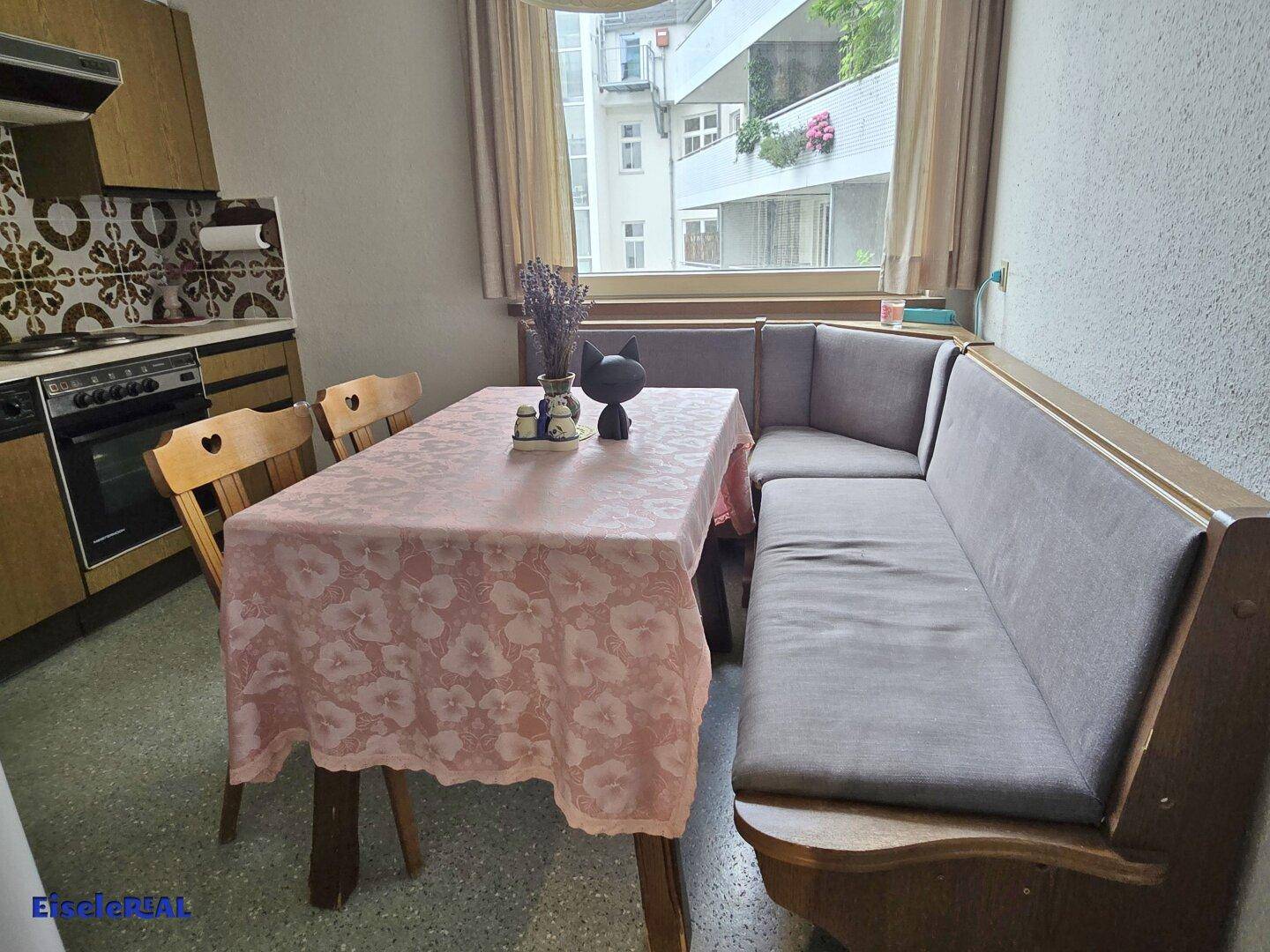 Essbereich in der Küche mit einer Eckbank, Esstisch und Blick nach draußen durch das Fenster.