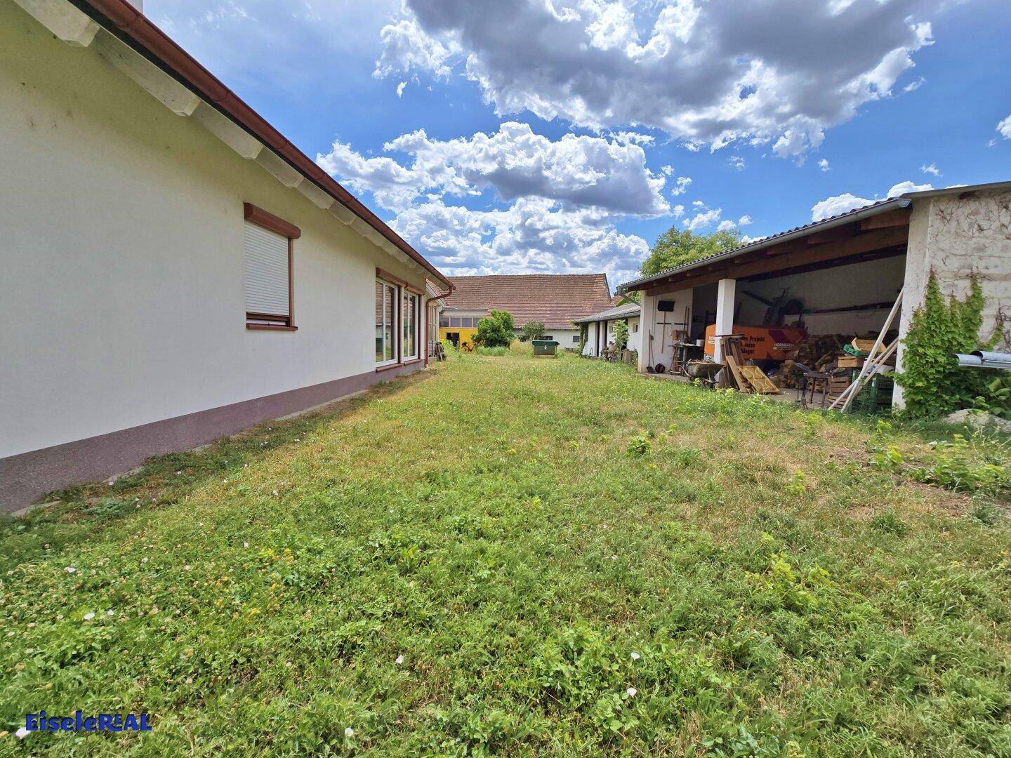 Seitenansicht des Hauses mit weitläufigem Rasen und einem Schuppen.