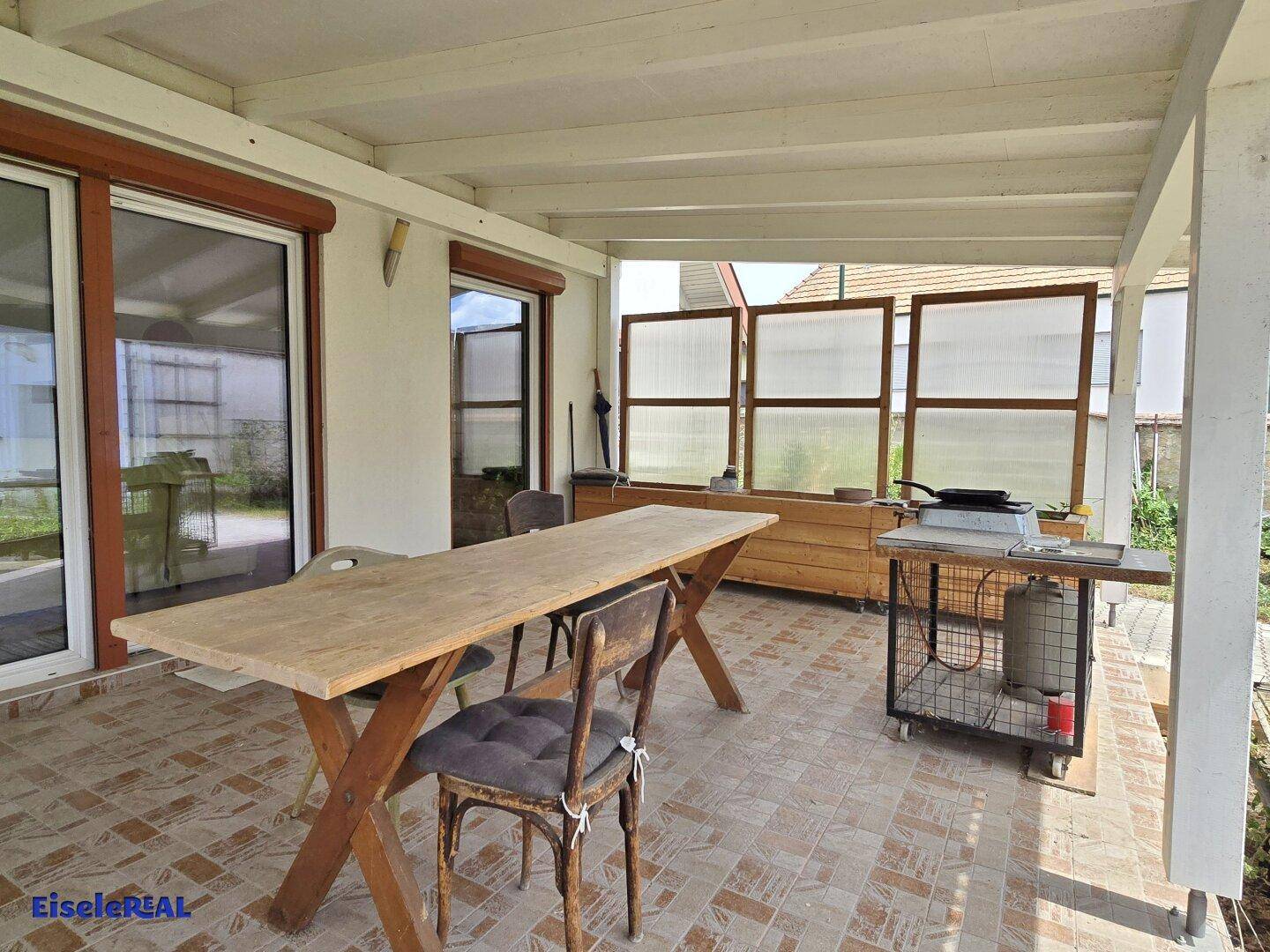 Überdachte Terrasse mit Esstisch und Grillbereich für gemütliche Stunden im Freien.