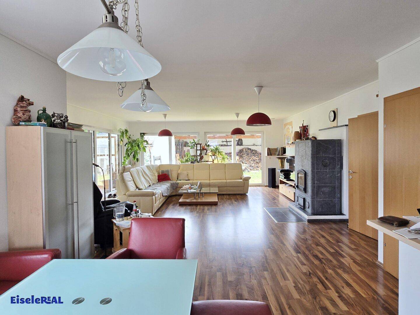 Offener Wohn- und Essbereich mit Kaminofen, Holzboden und Zugang zur Terrasse.